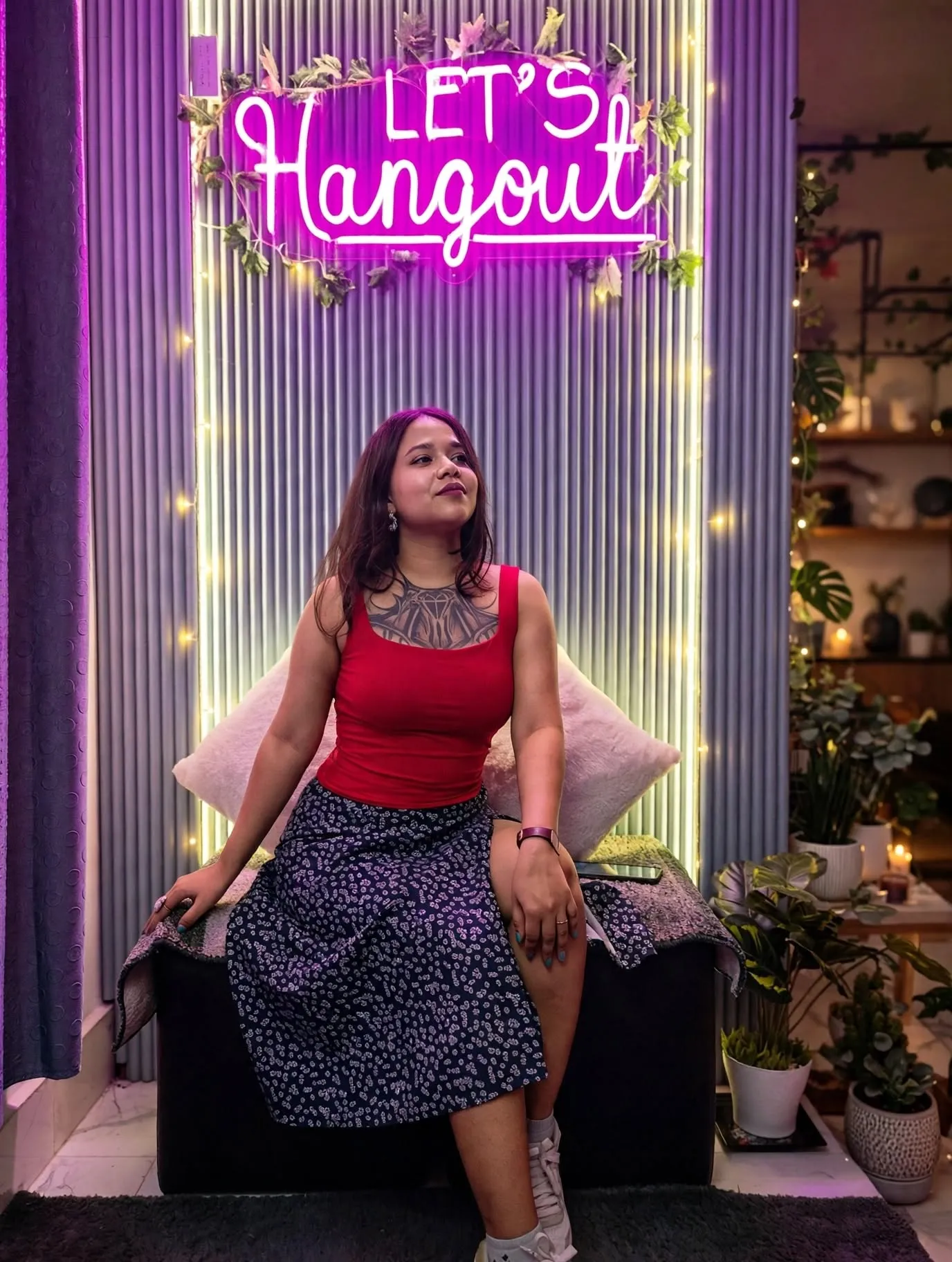 Prerna hand-poking a tattoo in a cozy neon studio